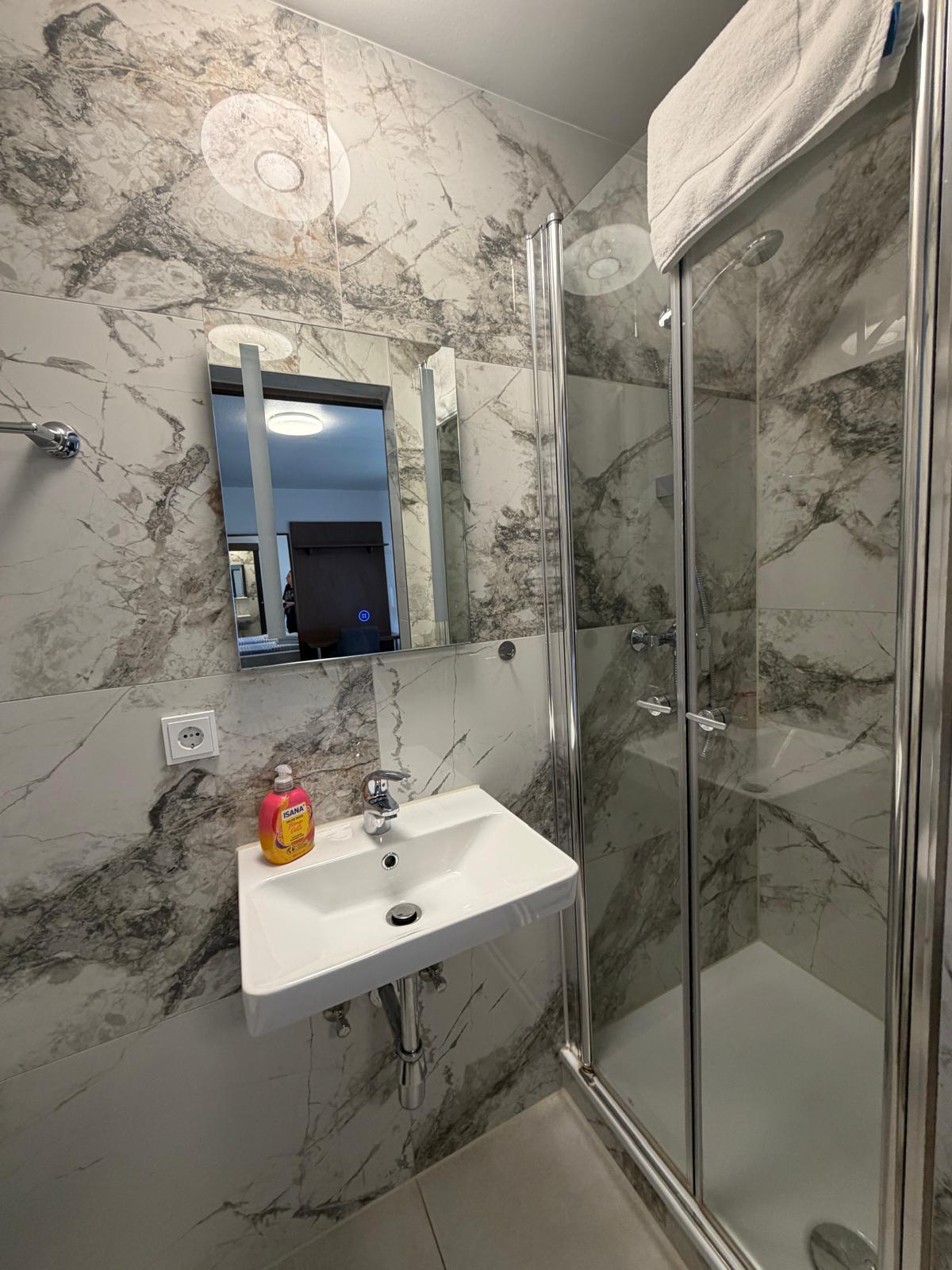 Bathroom with marble-look tiling and glass shower at Hotel Weller Dietzenbach