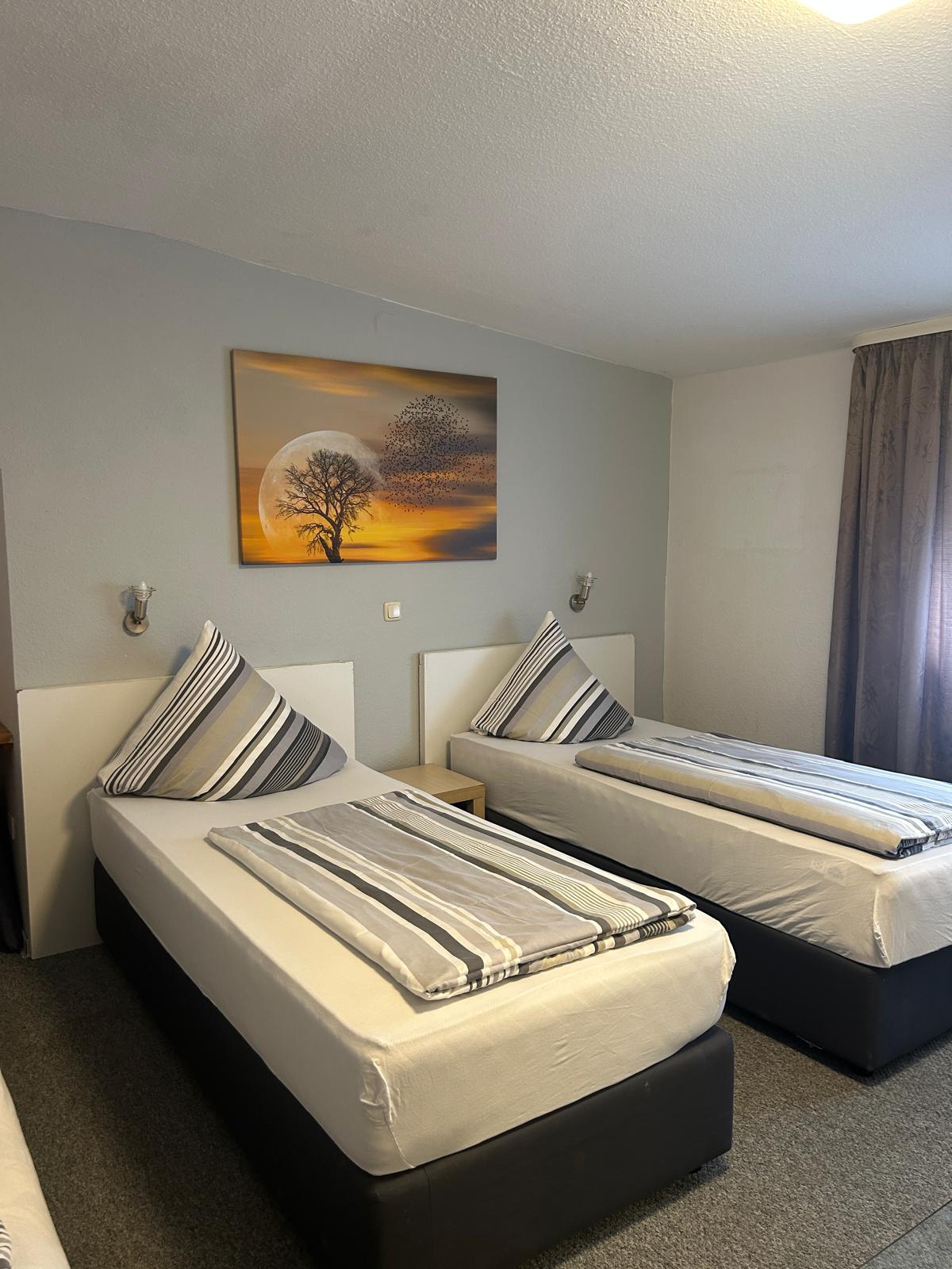 Twin room with reading lamps and bedside table at Hotel Weller Dietzenbach